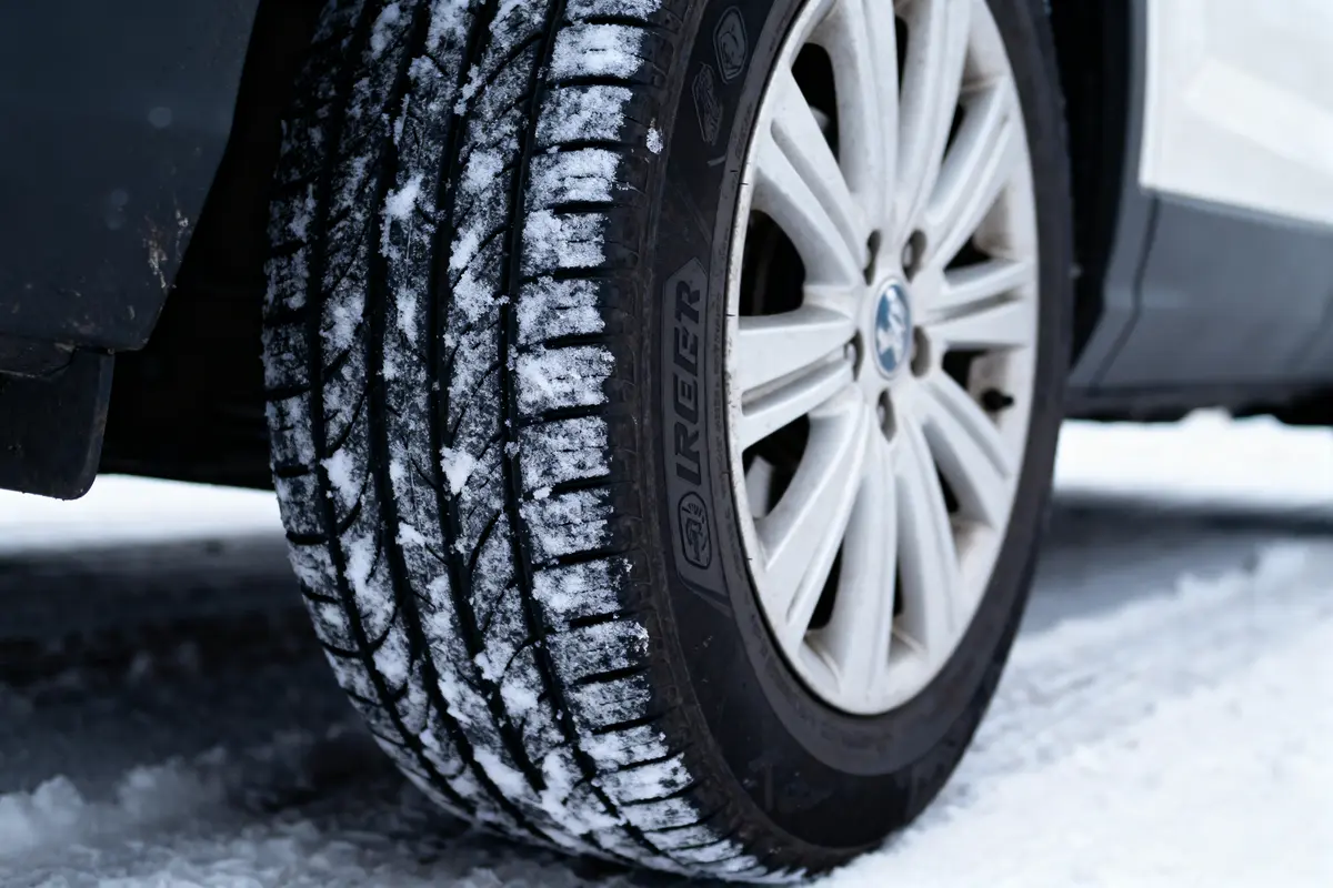 Pneu de voiture avec neige sur la bande de roulement, sur une route enneigée.