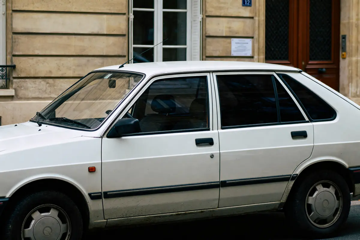 Voiture blanche avec vitres teintées illustrant la loi vitres teintees en milieu urbain